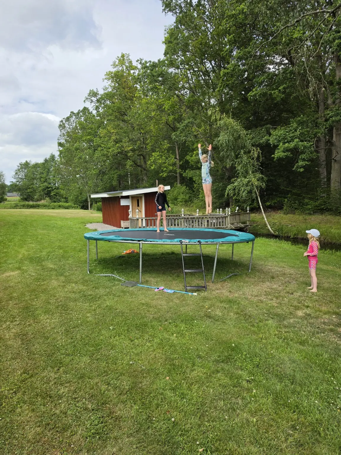 Barn som leker på trampolinen vid bastun och bäcken